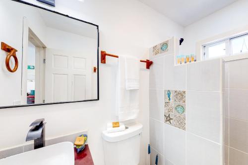 a white bathroom with a mirror and a toilet at DV 4 at DV Cabanas Gold Standard Certified in Caye Caulker