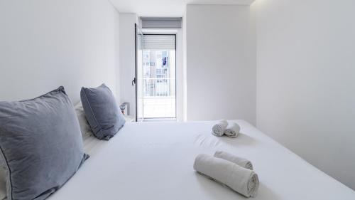 a white bedroom with a large white bed with pillows at Center Porto Nice Flat in Porto