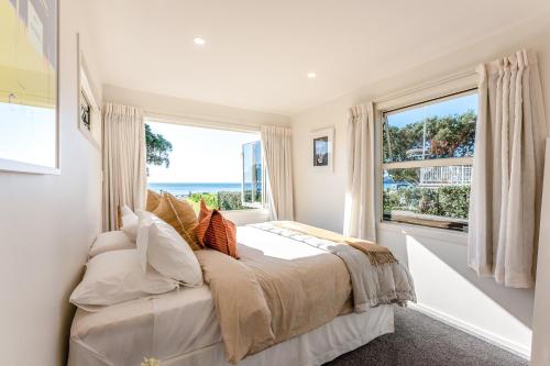 a bedroom with a bed and a large window at Onetangi Beachfront Escape - Coast & Country in Onetangi