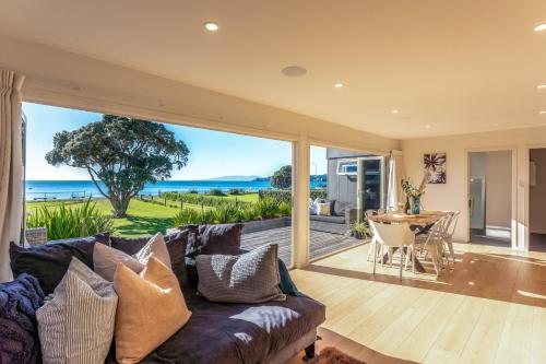 a living room with a couch and a view of the ocean at Onetangi Beachfront Escape - Coast & Country in Onetangi