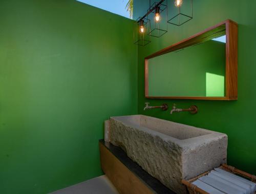 a green bathroom with a sink and a mirror at Sayulinda Hotel in Sayulita