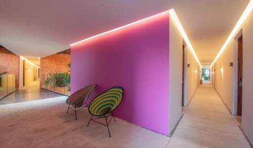 two chairs against a pink wall in a hallway at Sayulinda Hotel in Sayulita