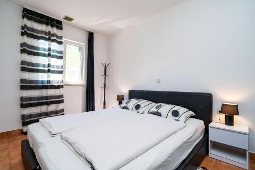 Un dormitorio con una gran cama blanca y una ventana en Apartments by the sea Zuljana, Peljesac - 10233, en Žuljana