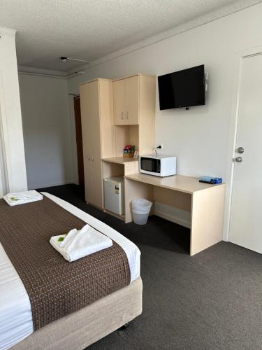 a hotel room with two beds and a desk with a microwave at Adelaide Airport Motel in Adelaide