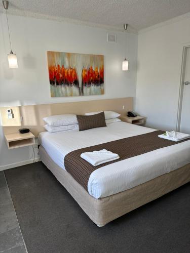 a bedroom with a large bed and a painting on the wall at Adelaide Airport Motel in Adelaide