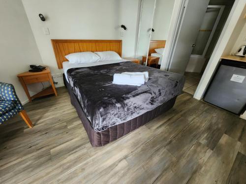 a bedroom with a bed and a wooden floor at The Beach Retreat Coolum in Coolum Beach