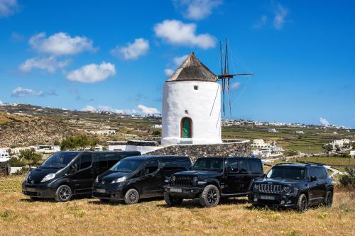 a group of four vehicles parked in front of a windmill at San Marino Suites by Calm Collection in Fira