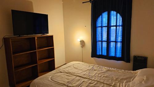 1 dormitorio con 1 cama, TV y ventana en El pomelo en Mendoza