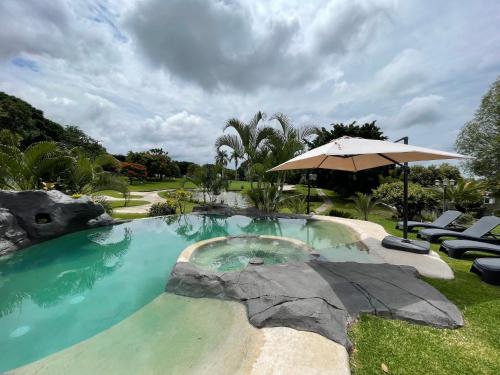 a swimming pool with an umbrella and chairs and an umbrella at Casa VIP con la mejor vista de Lomas de Cocoyoc in Texcalpan