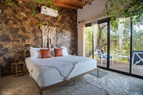 a bedroom with a bed and a stone wall at Boskenvid Hotel - Romantic Treehouses & Skypool in Valle de Guadalupe