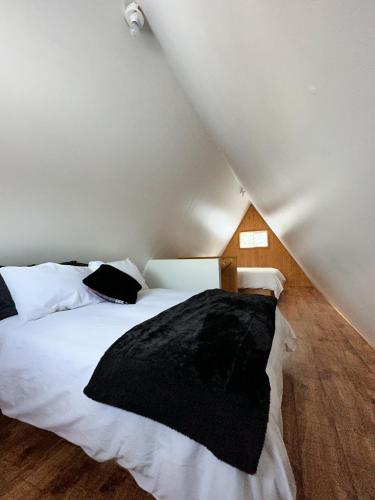 a bedroom with a white bed with a black blanket at OTIS Nature in Lamarche