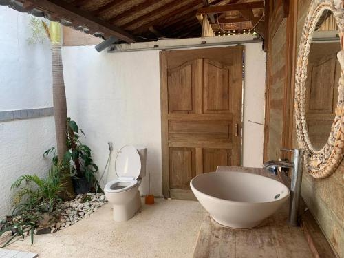 a bathroom with a tub and a toilet and a door at Villa Bakso Mentigi in Teluk Nara