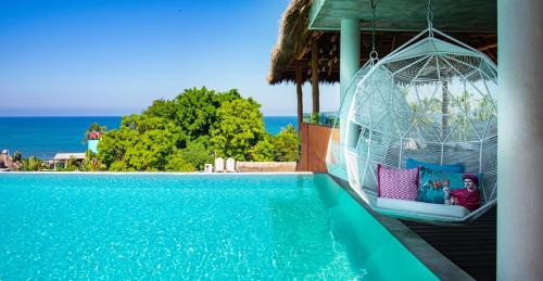 a woman sitting in a swing next to a swimming pool at Sayulinda Hotel in Sayulita