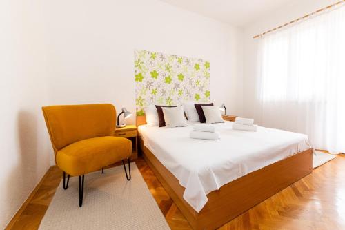 1 dormitorio con 1 cama y 1 silla en Apartment Mavarstica 17821b, en Trogir