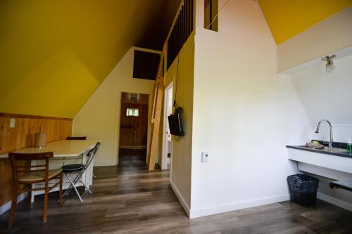 a kitchen and dining room with yellow walls and a table at OTIS Nature in Lamarche