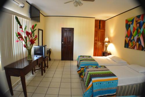 a hotel room with a bed and a table and a desk at Hotel Los Balcones de Chinandega in Chinandega