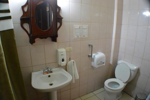 a bathroom with a sink and a toilet and a mirror at Hotel Los Balcones de Chinandega in Chinandega