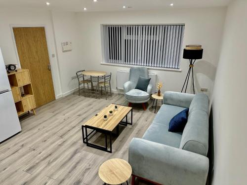 a living room with a blue couch and a table at Brand new Modern 1 bedroom bungalow with front & back gardens Central Headington in Oxford