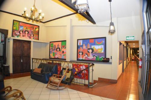 a living room with paintings on the walls and chairs at Hotel Los Balcones de Chinandega in Chinandega
