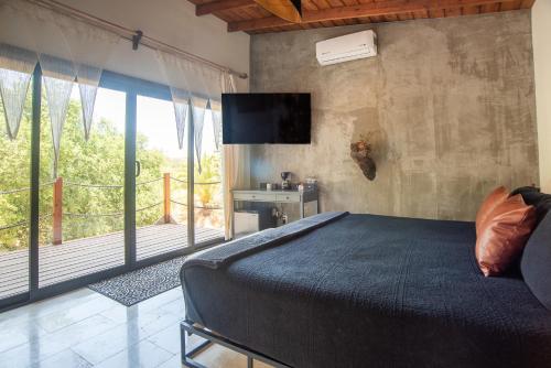a bedroom with a bed and a tv on the wall at Boskenvid Hotel - Romantic Treehouses & Skypool in Valle de Guadalupe