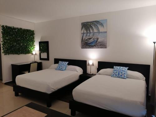 リオ・アトにあるPlaya Blanca SCのベッドルーム1室(ベッド2台付)が備わります。壁には絵画が飾られています。