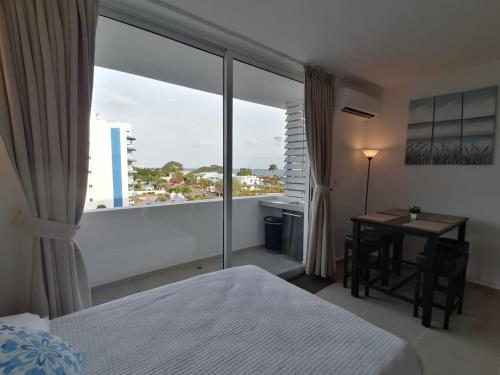 a bedroom with a bed and a desk and a large window at Playa Blanca SC in Río Hato