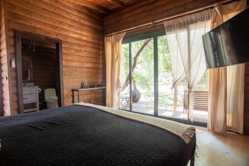 a bedroom with a bed and a large window at Boskenvid Hotel - Romantic Treehouses & Skypool in Valle de Guadalupe