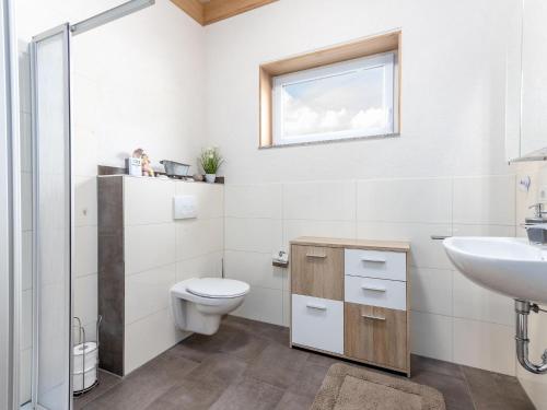 a bathroom with a toilet and a sink and a window at Lakeside Comfort in Hallschlag in Hallschlag