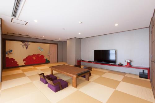 a living room with a table and a tv at Iwaiyado Jyuan Nikko Kawaji onsen in Nikko