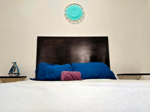 1 cama con almohadas azules y reloj en la pared en En el centro de Cancun, cerca del ADO, en Cancún