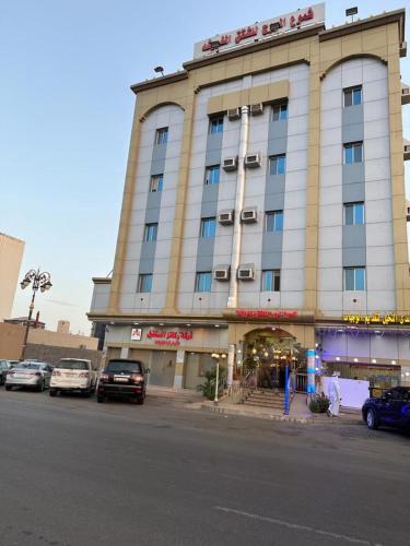 duży budynek z samochodami zaparkowanymi przed nim w obiekcie شموع المروج للوحدات الفندقية w mieście Tabuk