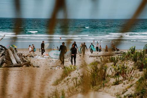 a group of people walking on the beach with surfboards at Gijon Surf Hostel in Gijón