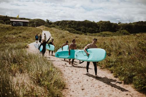 a group of surfers walking down a path with their surfboards at Gijon Surf Hostel in Gijón