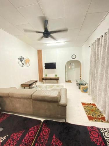 a living room with a couch and a ceiling fan at K.HOMESTAY @ KOK LANAS *aircond *3 bedrooms in Ketereh