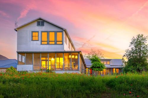 Ein Haus auf einem Hügel mit Sonnenuntergang im Hintergrund in der Unterkunft Medina River Historic Cottage in Castroville