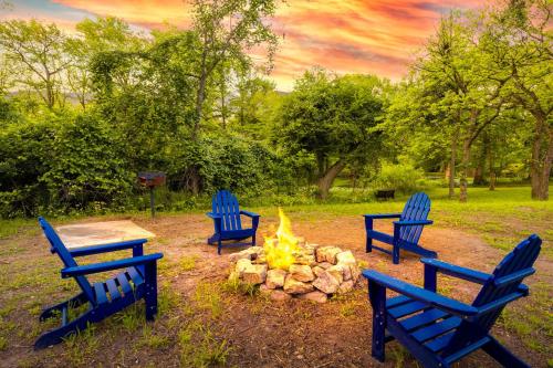 drei blaue Bänke rund um eine Feuerstelle in der Unterkunft Medina River Historic Cottage in Castroville
