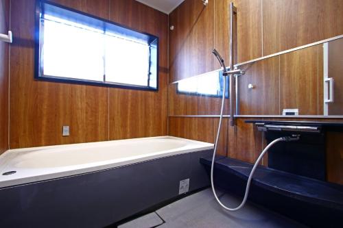 a bathroom with a bath tub and a window at Oasis Wadaura in Minamiboso