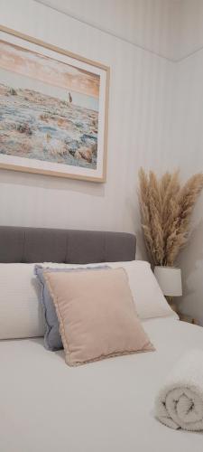 a bedroom with a white bed with a picture on the wall at Boutique Beach House in the HEART of St. Kilda in Melbourne