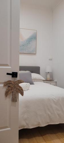 a bedroom with a white bed and a painting on the wall at Boutique Beach House in the HEART of St. Kilda in Melbourne
