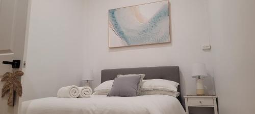 a white bedroom with a bed with towels on it at Boutique Beach House in the HEART of St. Kilda in Melbourne