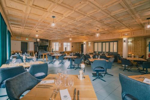 un restaurante con techos de madera, mesas y sillas en Terra-Beka Lodge en La Chapelle-dʼAbondance