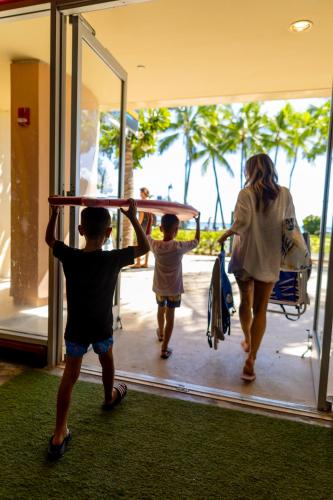 a woman and two children are carrying a table at The Twin Fin Hotel in Honolulu