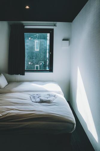 a bed in a room with a window at HOTEL TRAD Replay in Osaka