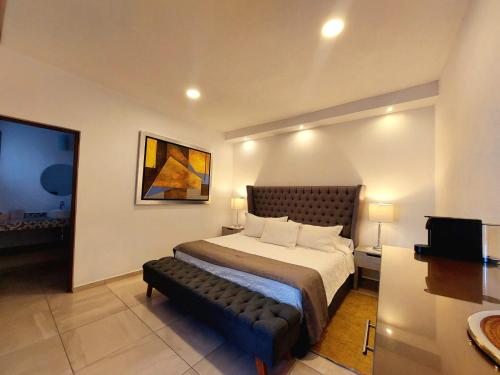 a bedroom with a bed with a bench in it at Casa Allende Morelia in Morelia
