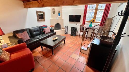 a living room with a black leather couch and a table at Casas de Guadalupe - Sante Fe Vacation Rentals in Santa Fe