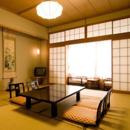 a living room with a couch and a table in a room at Hotel Kameya Honten in Chikuma
