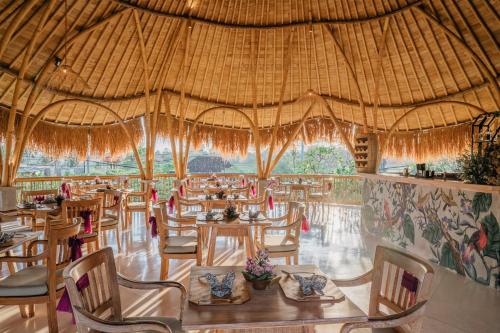 a restaurant with tables and chairs and a large straw roof at TheWakanda Resort A Pramana Experience in Ubud