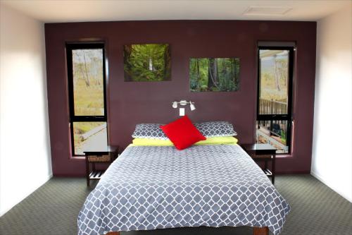 ein Schlafzimmer mit einem Bett mit einem roten Kissen in der Unterkunft Far South Eco-Cabin, Southern Tasmania in Lune River