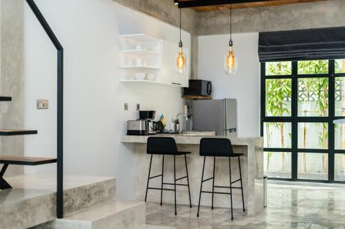 a kitchen with two bar stools and a counter at Berawa Lofts #2 Managed by CPM Bali in Canggu