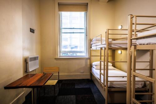 a room with bunk beds and a desk and a window at YHA Melbourne Central in Melbourne